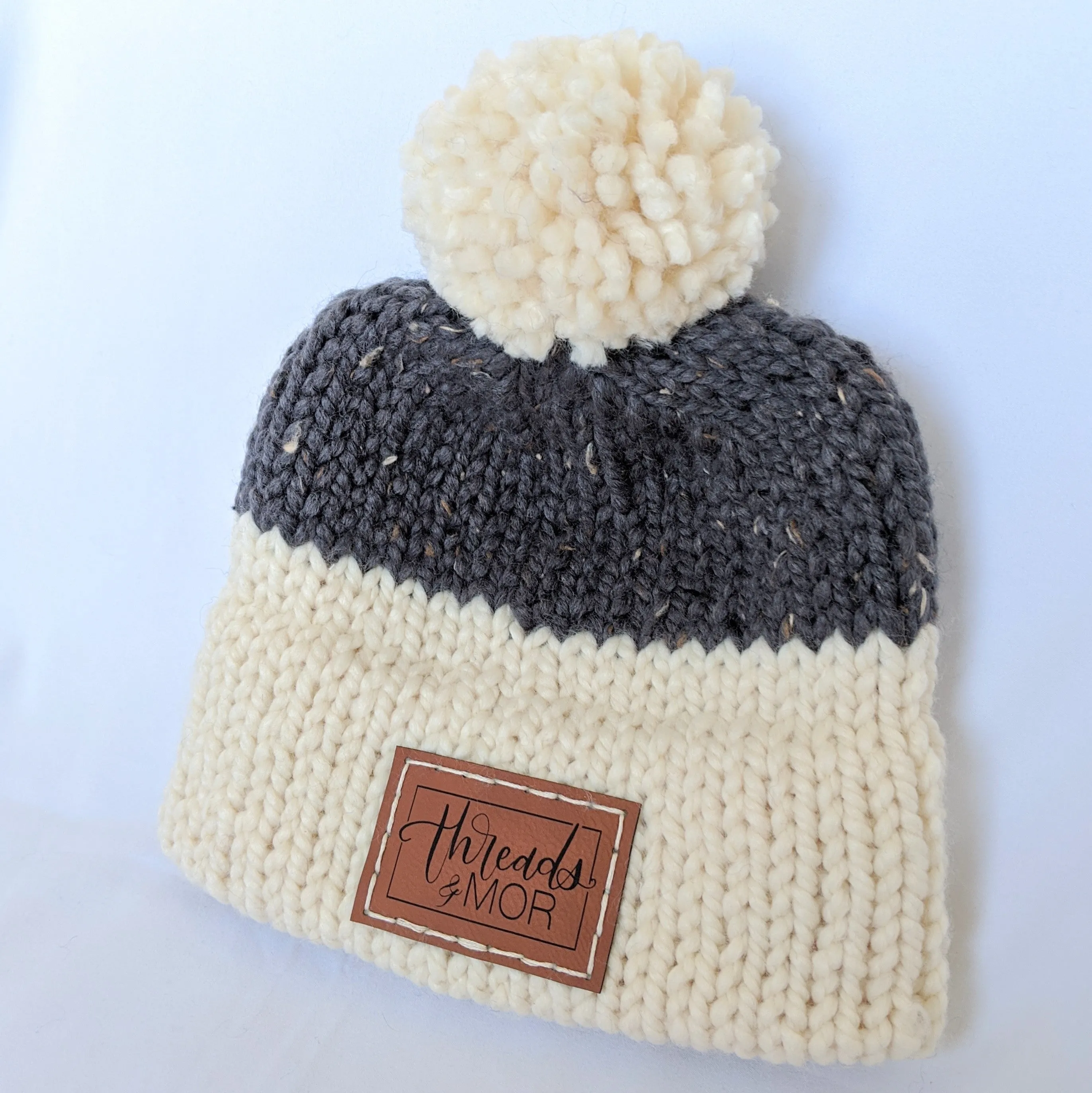 Gray and cream double brim knit hat with yarn pompom